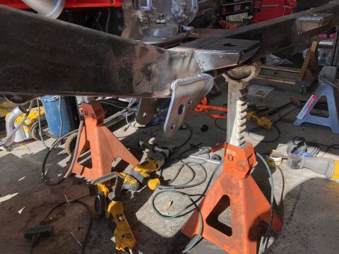 1992 Jeep Wrangler - Vehicle frame is supported by jack stands, with various tools like drills and grinders visible on the floor.