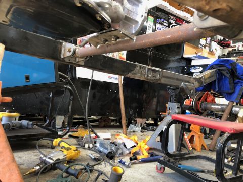 1992 Jeep Wrangler - Underbody drivetrain and suspension components are visible, supported by jack stands in a workshop setting.