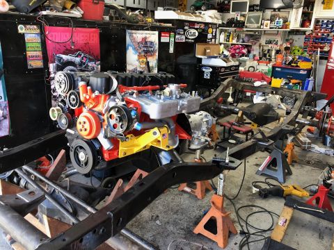 1992 Jeep Wrangler - Engine and chassis components are visible in a workshop setting, surrounded by tools and automotive parts.