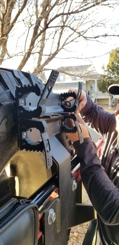 1996 Ford Bronco - A person is shown installing a step onto a vehicle's tire carrier assembly.