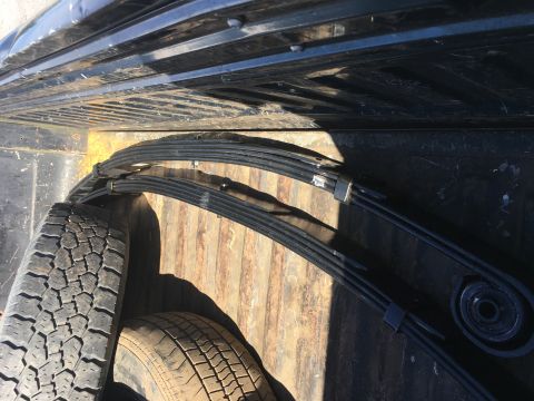 1967 Ford F-250 - Leaf springs and tires are stored in the bed of a truck.