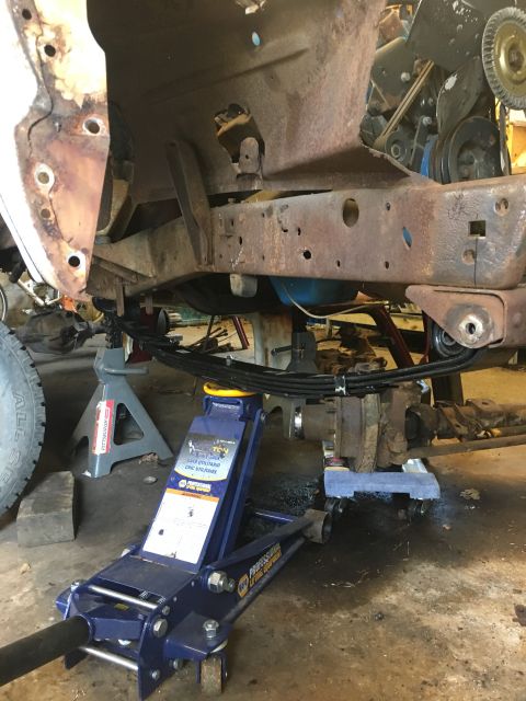 1967 Ford F-250 - Truck frame and suspension components are supported by jack stands and a hydraulic jack during maintenance.