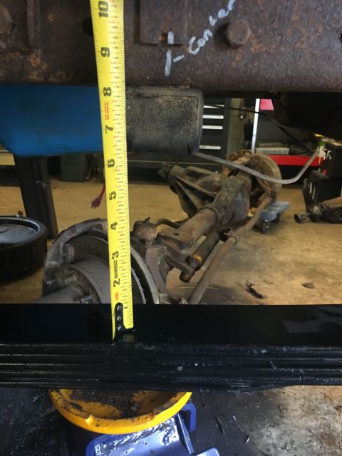 1967 Ford F-250 - Close-up of vehicle suspension components, including a leaf spring and axle, with a tape measure for scale.