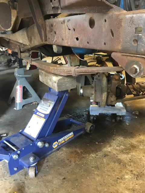 1967 Ford F-250 - Underbody view of a truck's frame and suspension components, including leaf springs, being worked on with jacks.