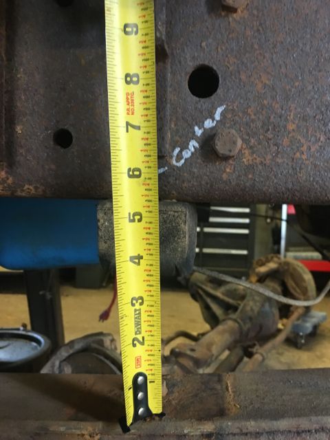 1967 Ford F-250 - Measuring tape shows dimensions on a rusty metal frame, possibly part of a vehicle's suspension system.