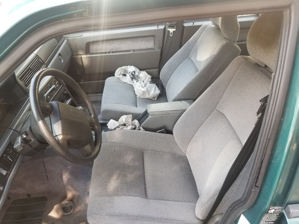 Interior view of a green car showing the front seats, steering wheel, and dashboard