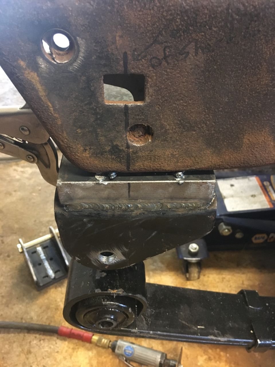Welded suspension part with scribe marks and a vise grip. Air tool in foreground