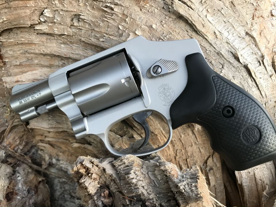 Silver revolver with black grip resting on wood. Text reads .38 SW SPL +P