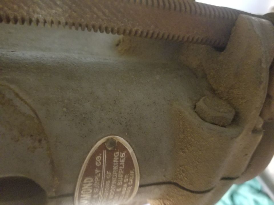 Close-up of a metal part with a red oval label that reads 'DIAMOND SUPPLY CO. MANUFACTURERS OF WOODWORKING & SUPPLIES' and an address