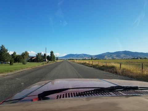 1985 Ford Bronco - Driving down a long, straight road with mountains in the distance.