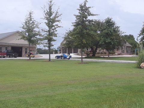 1994 Ford Bronco - Blue sports car and two trucks are visible on the property of a large house.