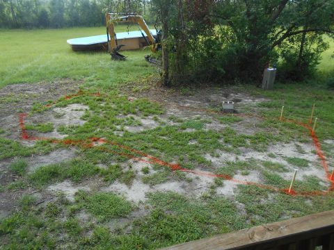 1992 Ford Bronco - An excavator sits in a grassy yard with orange construction lines marking out an area.