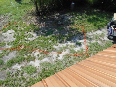 1992 Ford Bronco - Orange marking tape and stakes define a construction area on a patchy lawn, with a cinder block and a parked ATV nearby.