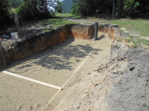 1992 Ford Bronco - A construction site shows a dug-out area prepared with gravel and marked with wood for a foundation or structure.
