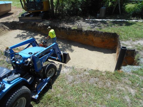 1992 Ford Bronco - Construction site with heavy machinery including a tractor and excavator, and a worker compacting soil.