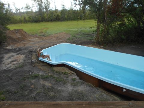 1992 Ford Bronco - A woman relaxes by a newly installed swimming pool in a grassy, undeveloped area.