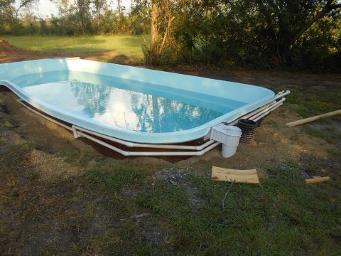 1992 Ford Bronco - An unfinished swimming pool is partially installed in a yard, with visible plumbing and filtration equipment.