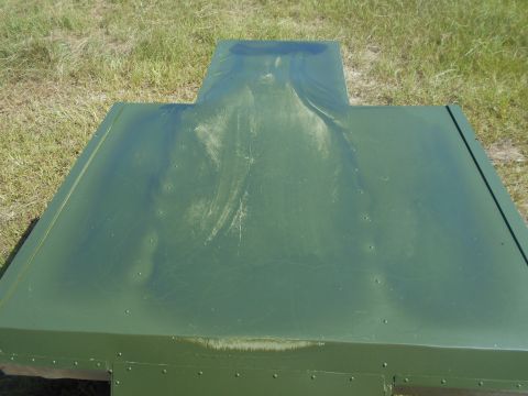 1992 Ford Bronco - Unidentified green painted metal part with a raised central section, photographed outdoors.