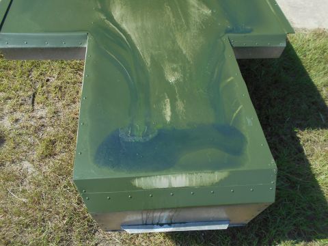 1992 Ford Bronco - A close-up view of a green metal container with visible rivets and staining on its surface.