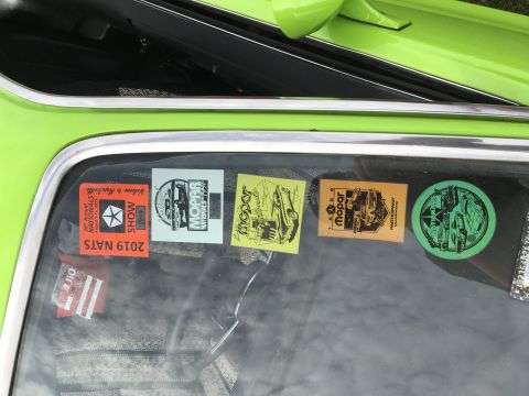 1974 Dodge Challenger - Several Mopar-themed stickers adorn the window of a green vehicle.