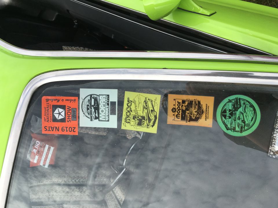 Car show event stickers on rear side window of green vehicle