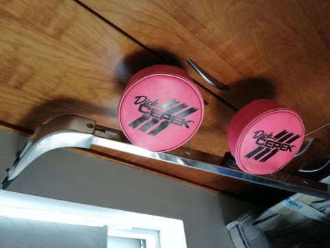 1996 Ford Bronco - Pink Dick Cepek tire covers with black lettering are stored on a shelf.