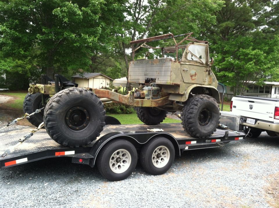 Olive green military truck with large tires on a trailer