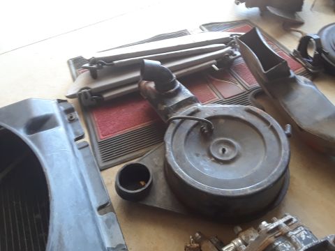 1994 Ford Bronco - Vehicle parts including an air cleaner and fan shroud are laid out on a mat.