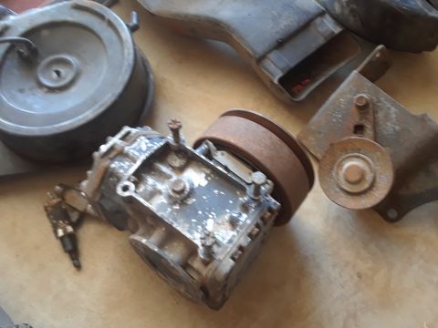 1994 Ford Bronco - A collection of aged automotive components, including a pulley and filter housing, are displayed on a flat surface.