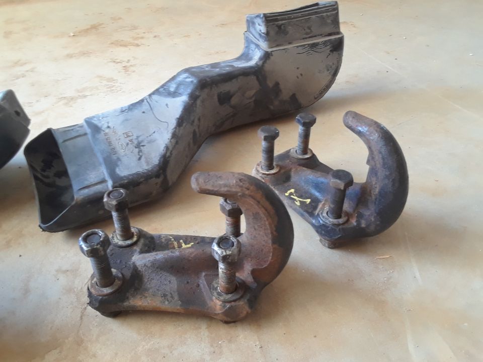 Two rusty tow hooks and a black plastic air intake duct