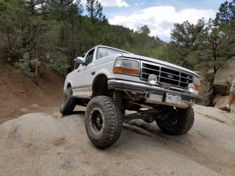 1995 Ford Bronco - This lifted 1995 Ford Bronco navigates a dusty, off-road trail with large tires and a modified suspension.