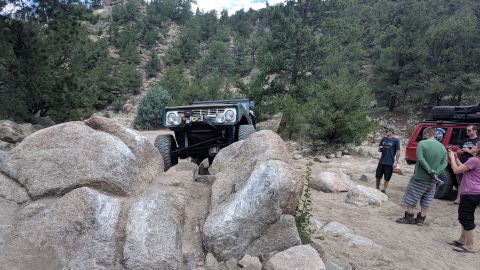 1995 Ford Bronco - A modified off-road vehicle navigates a rocky trail while onlookers observe the action.