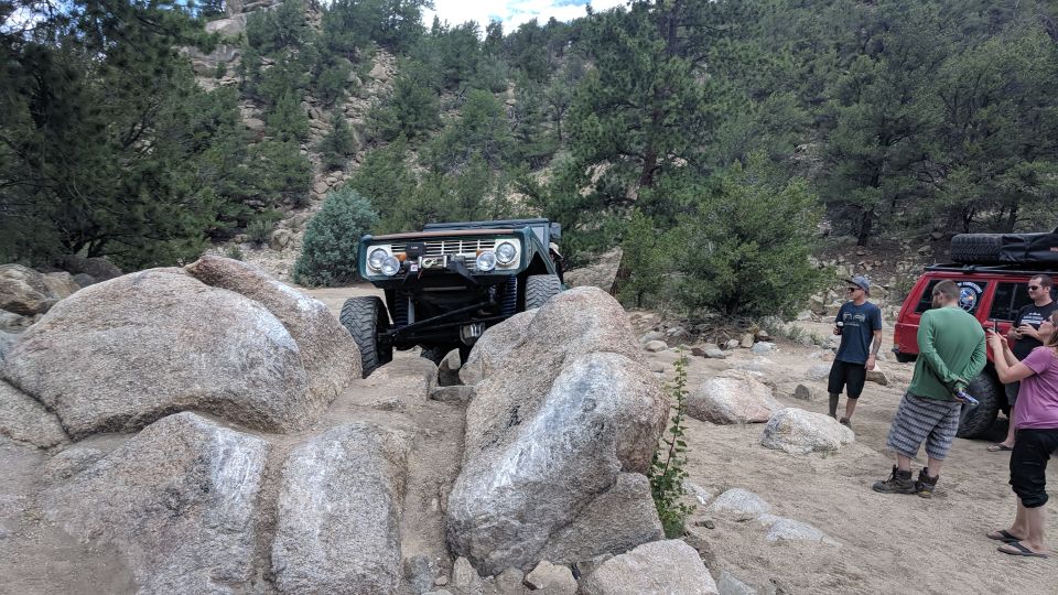 off-road vehicle climbing over rocks, people watching