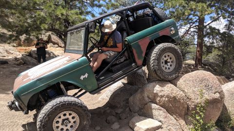 1995 Ford Bronco - This modified Ford Bronco navigates a rocky trail, showing its off-road capabilities.