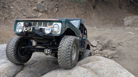 1995 Ford Bronco - This heavily modified off-road vehicle is shown navigating a rocky terrain.