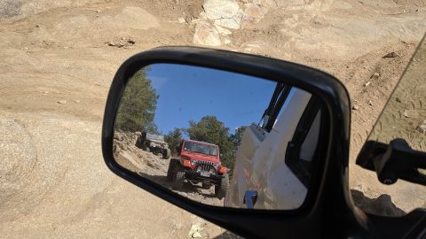 1995 Ford Bronco - Two Jeep Wranglers navigate a rocky off-road trail, seen reflected in a side mirror.