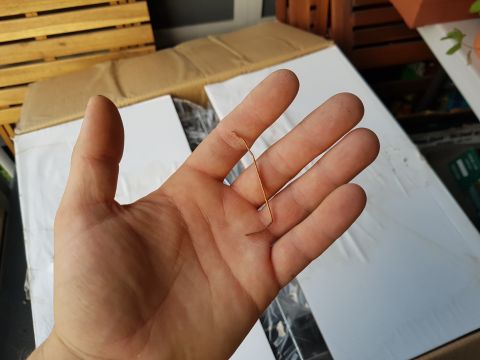 1978 Ford Bronco - A small, bent metal clip is held in a person's hand, with cardboard boxes visible in the background.