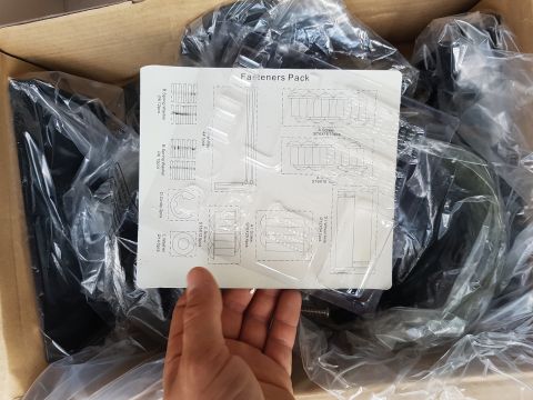 1978 Ford Bronco - A hand holds a diagram of a fasteners pack over a box of parts.