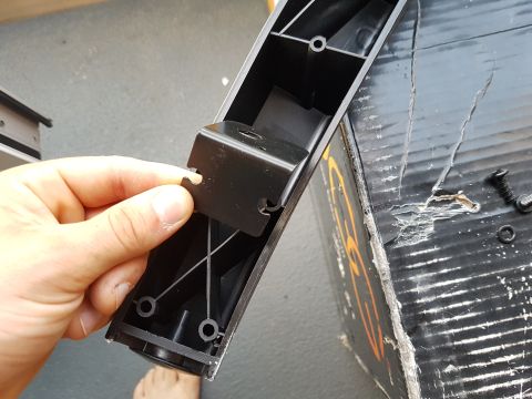 1978 Ford Bronco - A hand holds a detached black plastic bracket with a metal component, against a damaged black box.