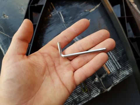 1978 Ford Bronco - An Allen wrench is held in a hand, with a black textured surface in the background.