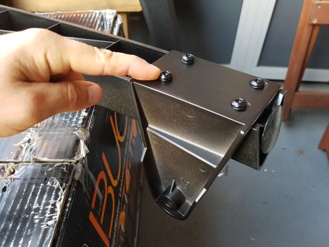 1978 Ford Bronco - Close-up of a hand interacting with a metal bracket, with partial text visible on a box.