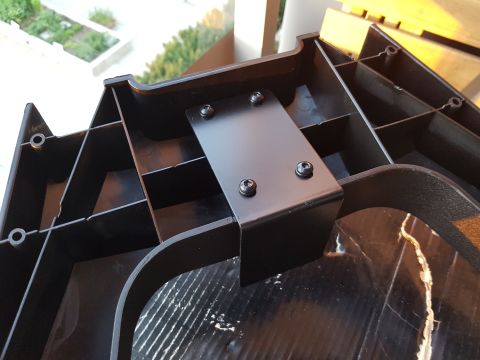 1978 Ford Bronco - A close-up view of a black plastic component with a metal bracket attached by screws.