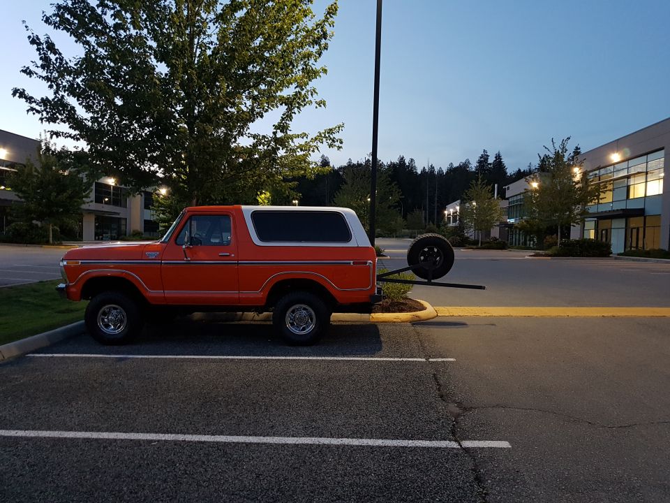 Orange 1978 Ford Bronco parked in a lot with a spare tire carrier at the rear