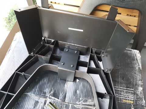 1978 Ford Bronco - A black plastic frame with metal brackets is shown from an underside angle, resting on a cardboard box.