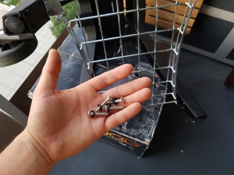 1978 Ford Bronco - Screws are being held in a hand, with a wire basket and a box in the background.