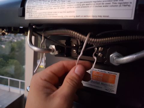 1978 Ford Bronco - Close-up of a gas regulator with a hand adjusting a wire, showing a label with product information.