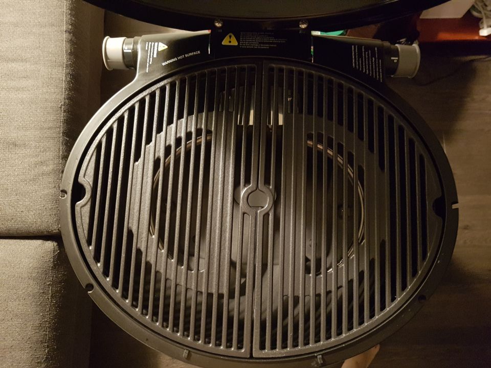 Round grill with metal grates, warning labels on the side