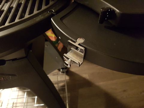 1978 Ford Bronco - A metal clip is attached to the side of a black grill part, with a wire rack visible below.