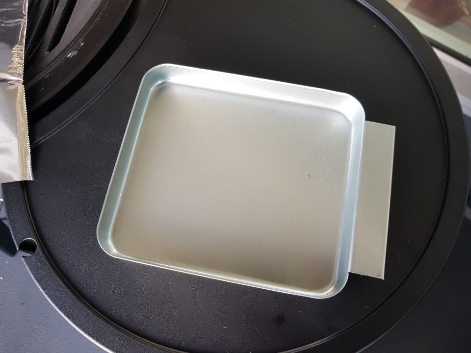 Metal tray on a black circular surface with a foil wrapper on the left