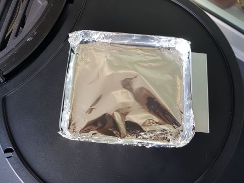 1978 Ford Bronco - A square aluminum foil pan containing food sits on a black grill grate, with the Supermotors.net logo visible in the lower right corner.